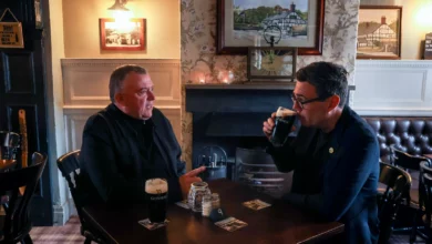 A busy pub interior in Greater Manchester with patrons seated at tables near the bar