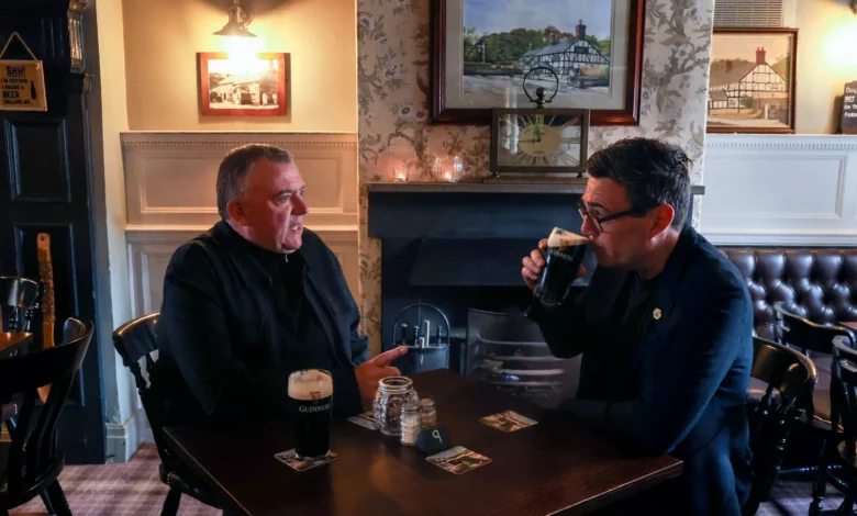 A busy pub interior in Greater Manchester with patrons seated at tables near the bar