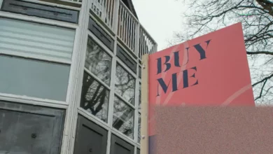 A row of modern flats in an English city, with estate agent For Sale signs outside several properties.