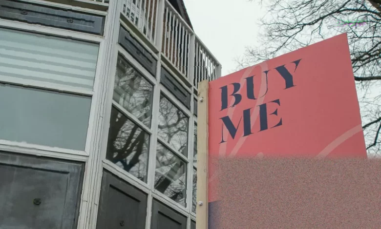 A row of modern flats in an English city, with estate agent For Sale signs outside several properties.