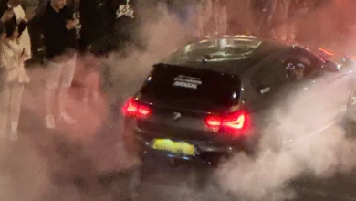 Night-time car meet on a central London street with spectators filming on phones