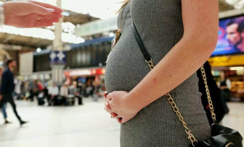 A woman in her forties looking at a pregnancy test in a bright living room