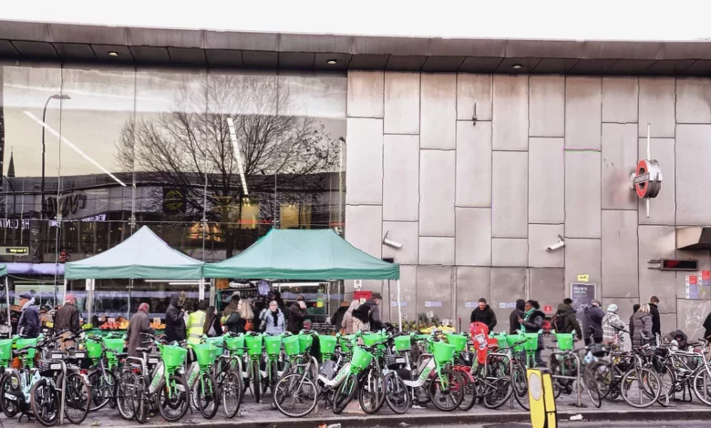 A row of abandoned hire e-bikes lying across a London pavement, blocking pedestrian access.