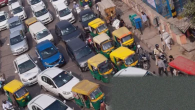 Smog-covered streets of Delhi with auto-rickshaws and scooters in traffic