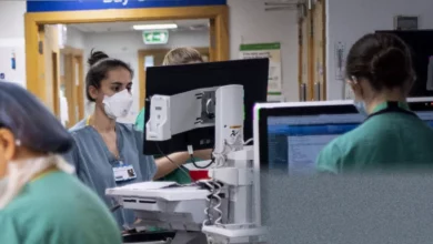 Overcrowded hospital corridor with patients on trolleys lining the walls