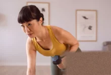 Woman in her forties performing a squat with dumbbells at home