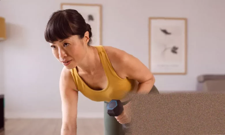 Woman in her forties performing a squat with dumbbells at home
