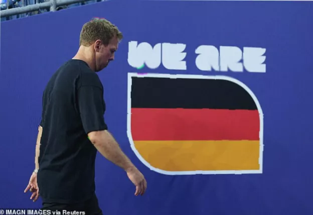 Empty stadium seats and a departing German fan holding a flag after the World Cup elimination