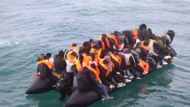 Overcrowded dinghy crossing the English Channel with passengers sitting along the sides