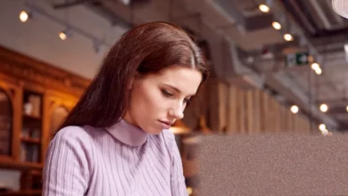 A young person staring at a laptop screen showing a fraudulent job offer email