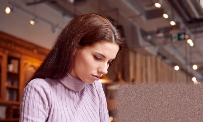 A young person staring at a laptop screen showing a fraudulent job offer email