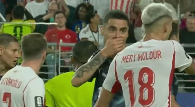England midfielder Jude Bellingham covering his mouth while speaking to a Ghana player on the pitch.