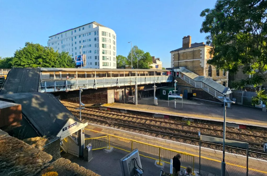 Aerial view of the station next to a busy road bridge and railway tracks