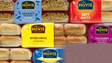 A bakery worker stacking sliced bread loaves on a shop shelf