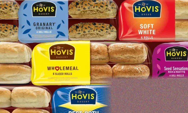 A bakery worker stacking sliced bread loaves on a shop shelf