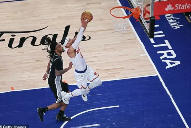 Basketball players battling for a rebound under the net during a tense final possession.