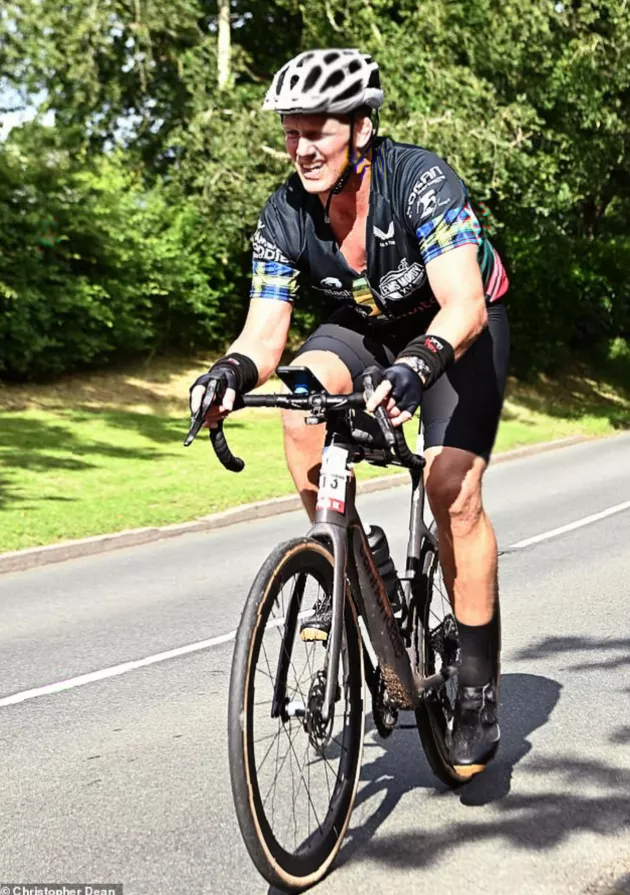 Support vehicles and cyclists paused at a red light in the countryside, with music playing from a speaker.