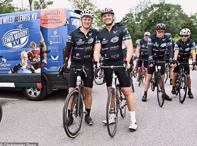 The peloton arriving at a rugby stadium, greeted by a small crowd of spectators and well-wishers.