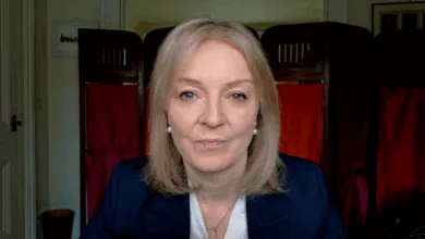 Liz Truss speaking at a political event, gesturing while addressing an audience.