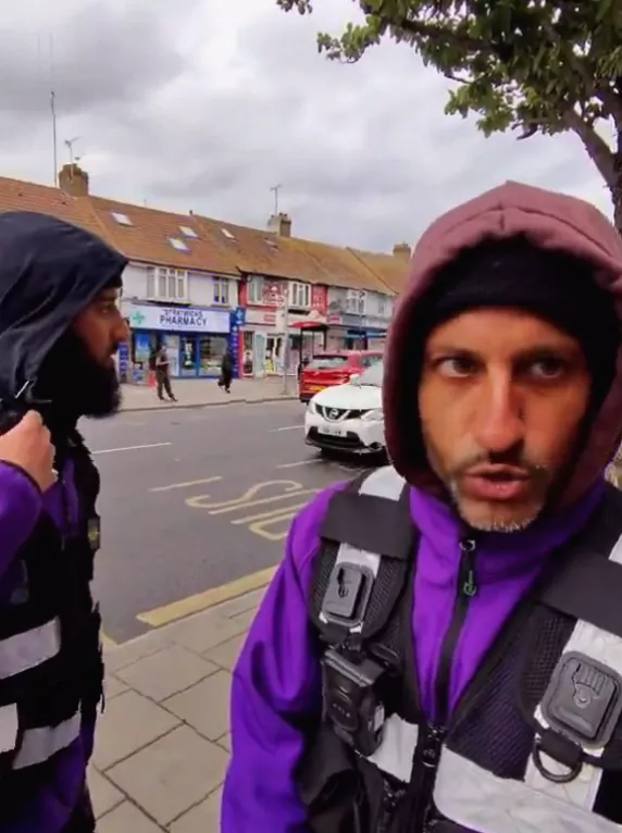 A red-hooded worker gestures across a road in Harrow while issuing violent threats to a member of the public