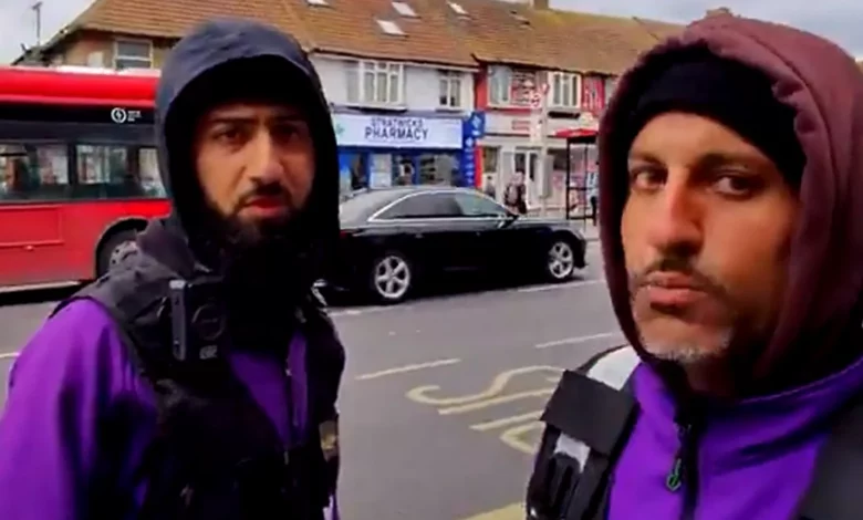 Two enforcement officers in branded jackets with hoods up confront a person in a Harrow bus lane
