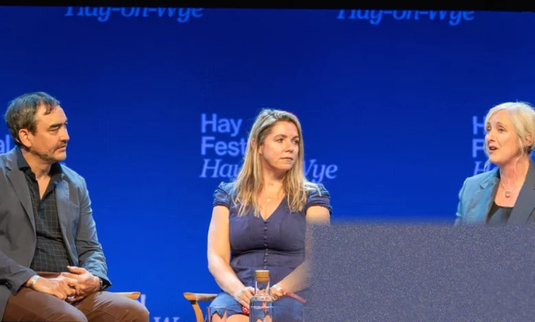 A silent author sitting on stage at the Hay Festival while the audience watches
