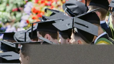 Students walking across a university campus with backpacks between red-brick buildings