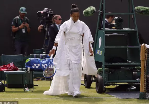 Crowd watches as a player removes a trailing tulle bow and outer kimono after a match