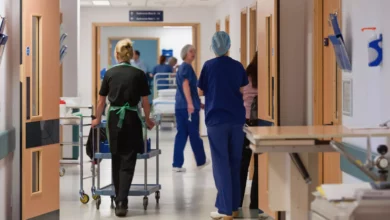 An NHS hospital corridor lined with patients on trolleys due to overcrowding