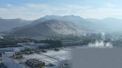 Aerial view of a large datacentre complex with cooling towers and solar panels nearby