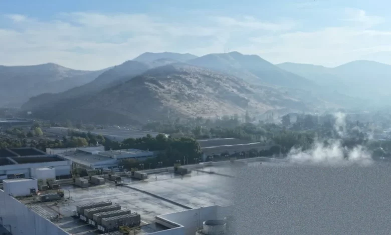 Aerial view of a large datacentre complex with cooling towers and solar panels nearby