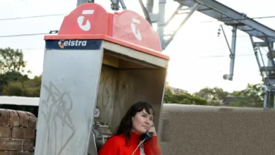 An orange payphone booth standing on a quiet suburban street in Australia