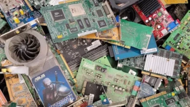 Office workers inspecting a pile of discarded laptops and monitors in a recycling centre