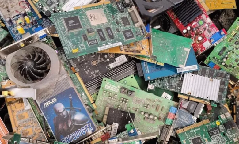 Office workers inspecting a pile of discarded laptops and monitors in a recycling centre