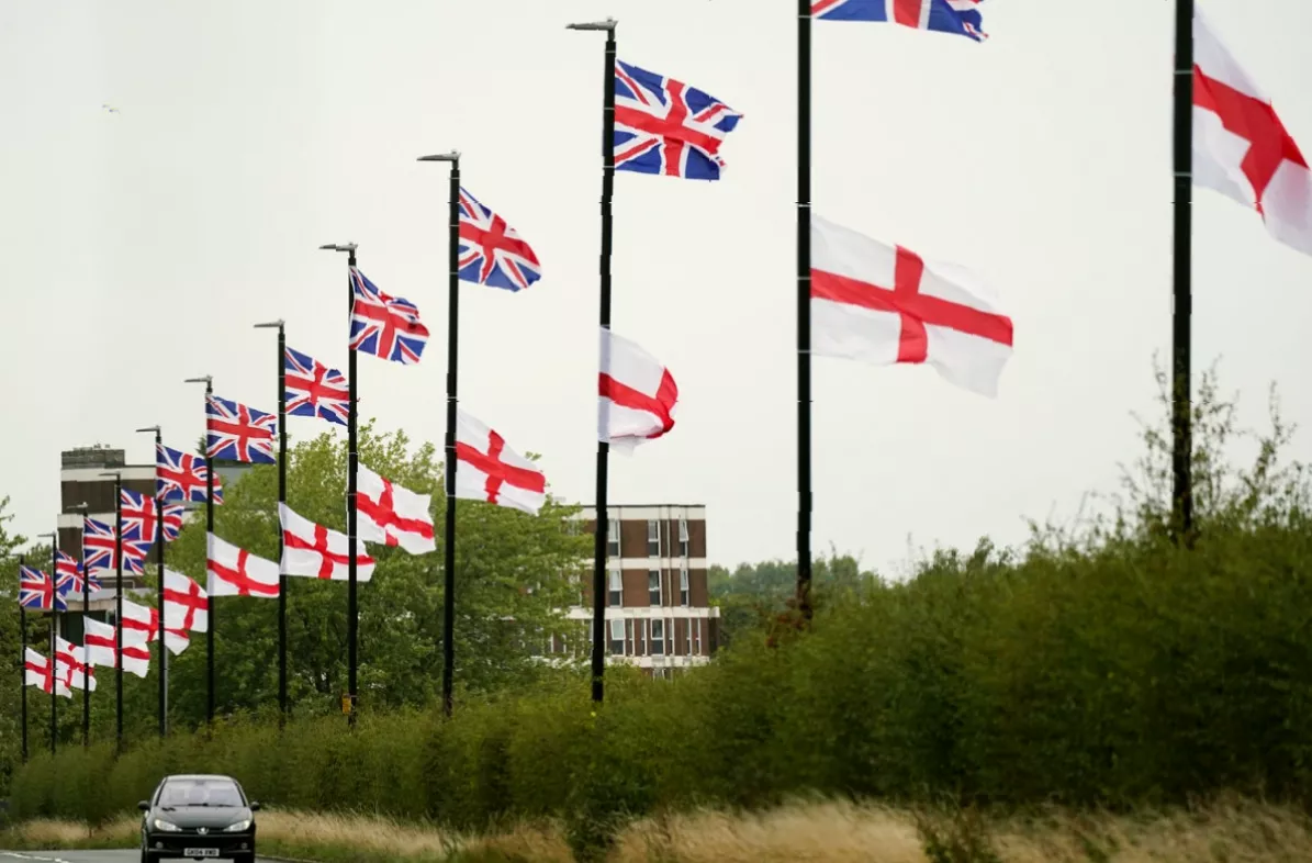 Council workers removing flags from highway lampposts in a suburban area