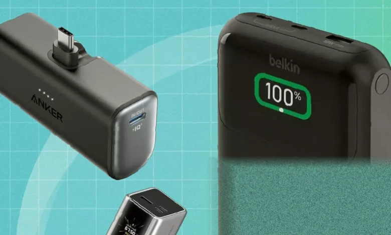 A collection of various power banks and battery packs arranged on a wooden table for testing.