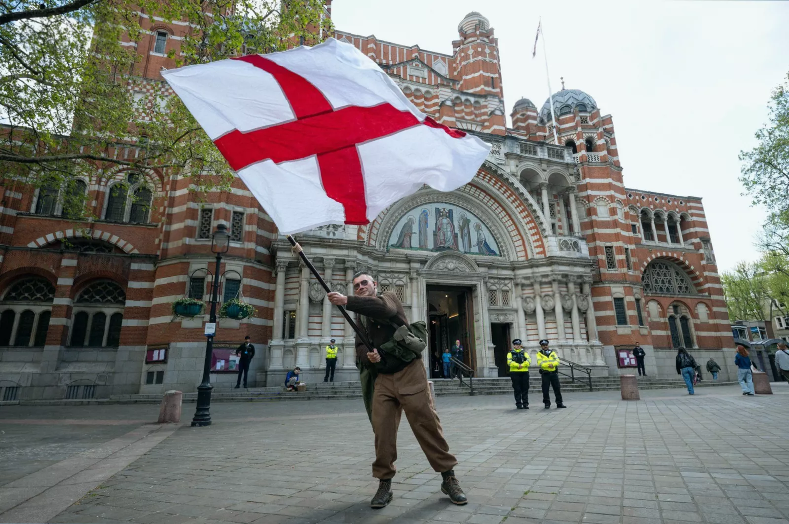 St George’s Cross flag flying from a flagpole in east London against a cloudy sky.