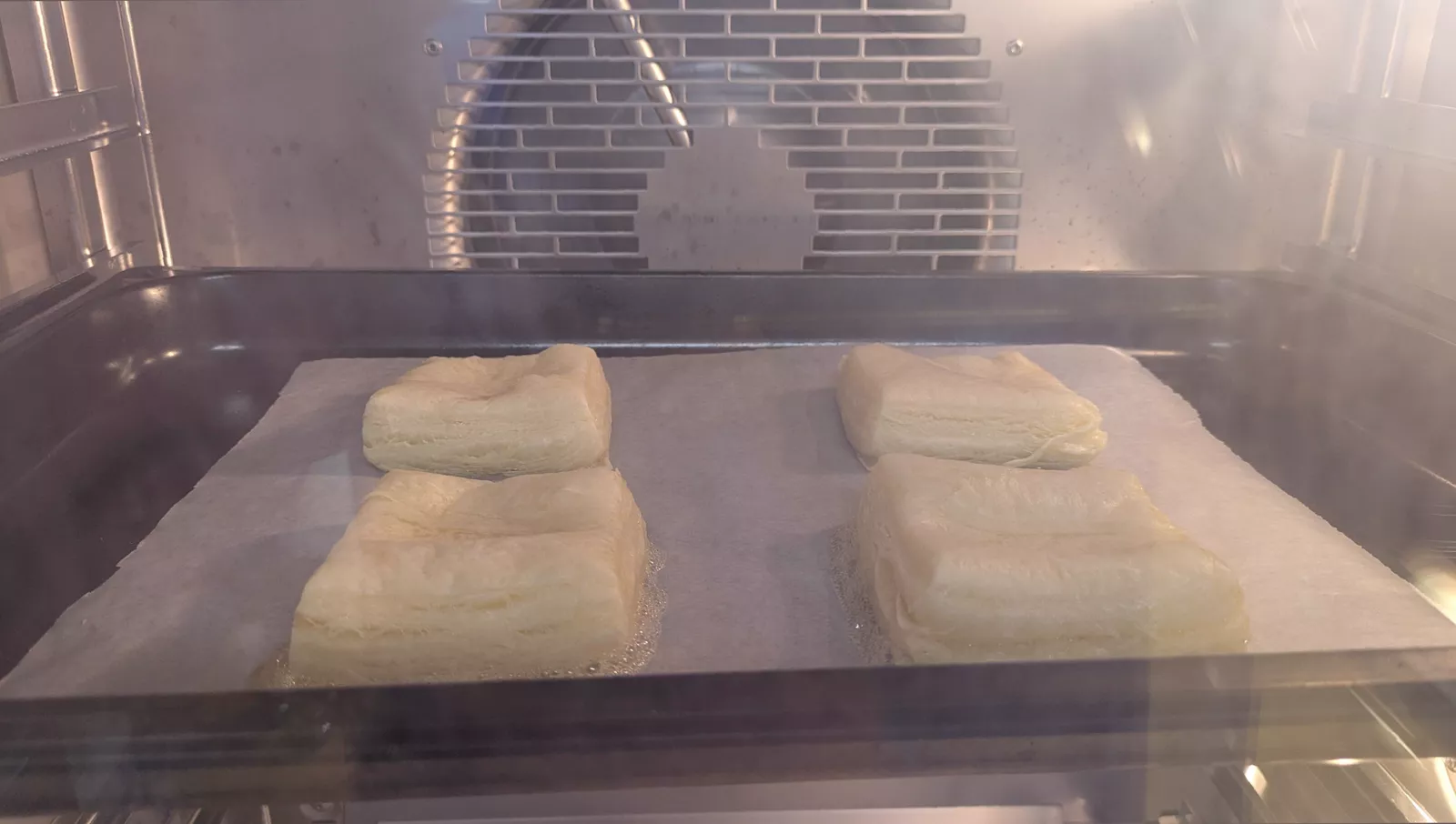 A freshly baked sausage roll on a wire cooling rack in a test kitchen