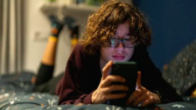 Teenagers looking at social media feeds on smartphones in a school common room