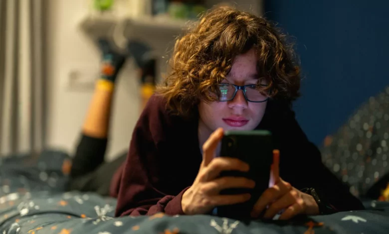 Teenagers looking at social media feeds on smartphones in a school common room