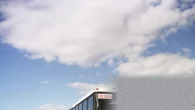 A Greyhound bus parked at a dilapidated intercity station with passengers waiting