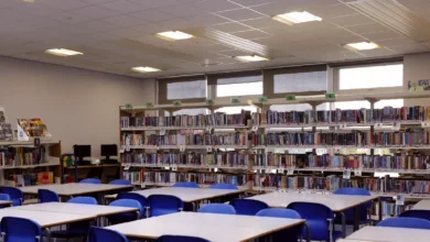 A secondary school library with shelves of children's books, some labelled for primary ages