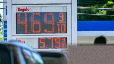 A petrol station forecourt showing fuel prices on a digital display board.