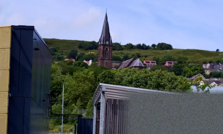 Sheep grazing on rewilded land beside empty modern technology buildings in Ebbw Vale
