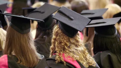 A university graduation ceremony in a UK campus hall, with graduates in caps and gowns.