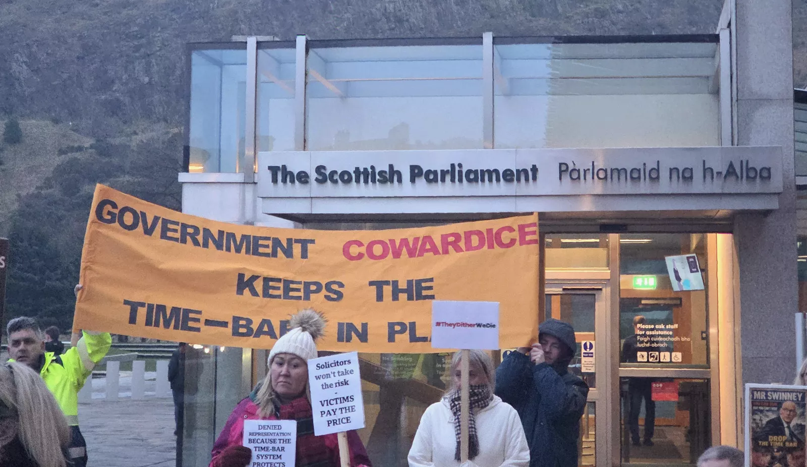 Crowd of protesters holding placards outside the Scottish Parliament over inquiry delays