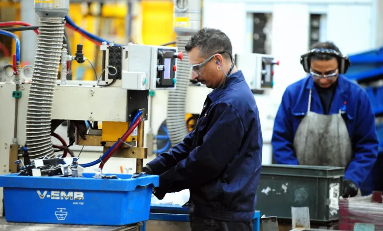 Factory production line with workers assembling components under bright industrial lighting