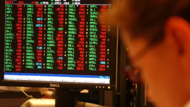 Traders monitoring stock prices on electronic boards at the London Stock Exchange