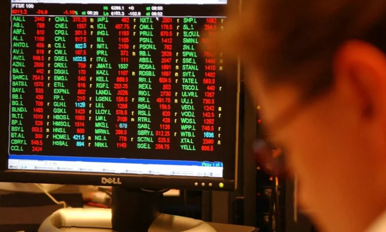 Traders monitoring stock prices on electronic boards at the London Stock Exchange