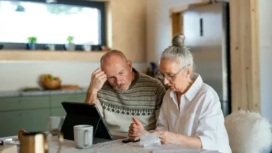 An elderly couple reviewing financial documents at a kitchen table